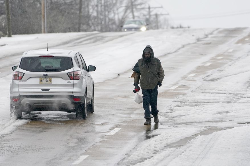 With many of the downtown sidewalks covered with ice and impassable, this pedestrian takes to walking along Fortification Street as cars pass him Wednesday, Feb. 17, 2021, in Jackson, Miss., as light snow mixed with sleet, and rain continue to cover much of the state. The National Weather Service in Jackson has issued a winter storm warning for parts of Mississippi effective 6 a.m. Wednesday ahead of another storm system set to impact the region. (AP Photo/Rogelio V. Solis)