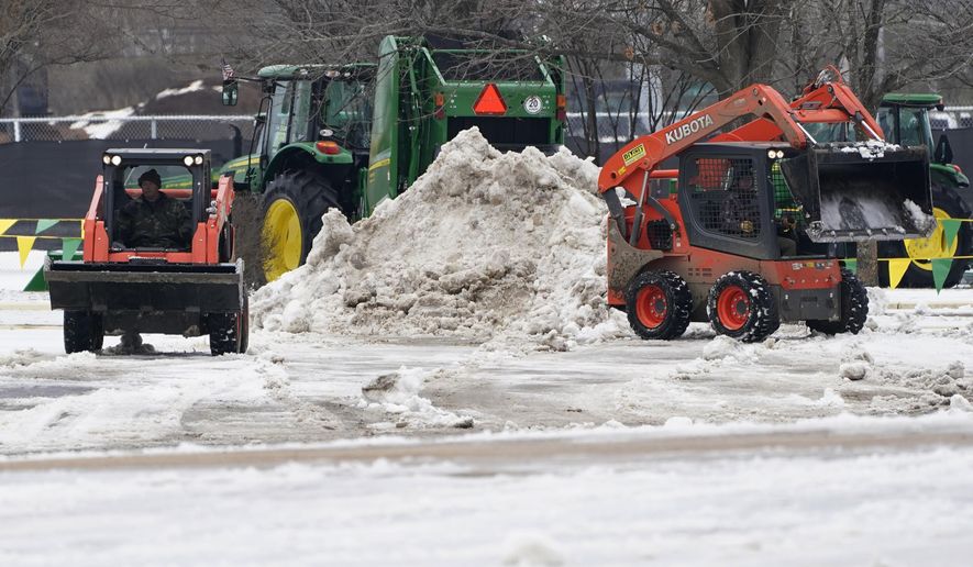 A grounds crew use compact tractors to remove the ice and snow that covered parking spaces, Wednesday, Feb. 17, 2021, at the Mississippi State Fairgrounds in Jackson, Miss., as light snow mixed with sleet, and rain continue to cover much of the state. In spite of the inclement weather, Wednesday's performance of the Dixie National Rodeo is taking place as scheduled. The National Weather Service in Jackson has issued a winter storm warning for parts of Mississippi ahead of another storm system set to impact the region. (AP Photo/Rogelio V. Solis)