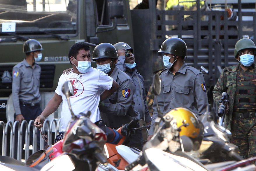 A man is held by police during a crackdown on anti-coup protesters holding a rally in front of the Myanmar Economic Bank in Mandalay, Myanmar, Monday, Feb. 15, 2021. Security forces in Myanmar intensified their crackdown against anti-coup protesters on Monday, seeking to quell the large-scale demonstrations calling for the military junta that seized power earlier this month to reinstate the elected government. (AP Photo)