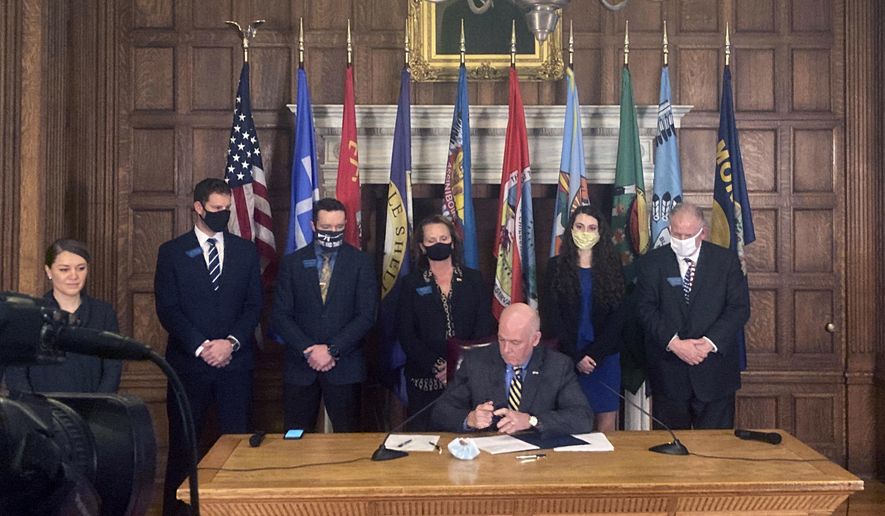 Montana Gov. Greg Gianforte, center, signs HB102 on Thursday, Feb. 18. 2021, in the State Capitol in Helena, Mont. The bill allows concealed firearms to be carried in most places in the state without a permit, and expands the list of places where guns can be carried to include university campuses and the state Capitol. (AP Photo/Iris Samuels)
