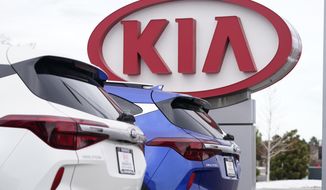 FILE - In this Sunday, Dec. 20, 2020, file photo the company sign stands over a row of unsold 2021 Seltos models at a Kia dealership, in Centennial, Colo. Kia Motors America says it’s restoring services crippled by a computer network outage that began Saturday, Feb. 13, 2021, and which apparently affected dealers’ ability to order vehicles and parts and knocked offline a smartphone app that owners use to remotely start and warm up vehicles. (AP Photo/David Zalubowski, File)