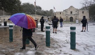 Snow begins to accumulate as San Antonio police officers gather near the Alamo, Thursday, Feb. 18, 2021, in downtown San Antonio. Snow, ice and sub-freezing weather continue to wreak havoc on the state&#39;s power grid and utilities. (AP Photo/Eric Gay)