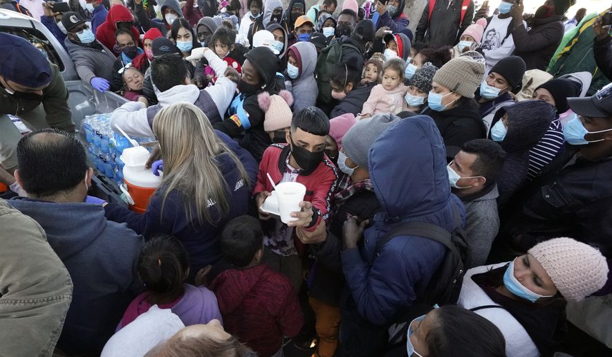 Asylum seekers receive food as they wait for news at the border, Friday, Feb. 19, 2021, in Tijuana, Mexico. After waiting months and sometimes years in Mexico, people seeking asylum in the United States are being allowed into the country starting Friday as they wait for courts to decide on their cases, unwinding one of the Trump administration&#39;s signature immigration policies that President Joe Biden vowed to end. (AP Photo/Gregory Bull)