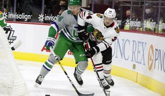 Carolina Hurricanes&#x27; Jake Bean (24) and Chicago Blackhawks&#x27; Carl Soderberg (34) battle for the puck during the first period of an NHL hockey game in Raleigh, N.C., Friday, Feb. 19, 2021. (AP Photo/Karl B DeBlaker)