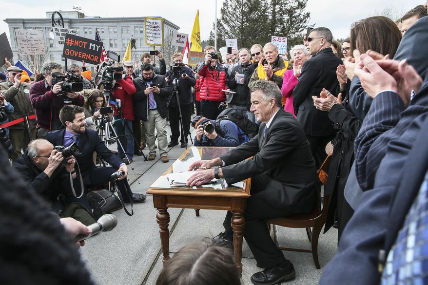 FILE - In this April 11, 2018 file photo, Vermont Gov. Phil Scott finishes signing a gun restrictions bill on the steps of the Statehouse in Montpelier, Vt. On Friday, Feb. 19, 2021, the Vermont Supreme Court upheld the legality of the portion of the 2018 legislation that restricts the size of large-capacity ammunition magazines for firearms. (AP Photo/Cheryl Senter, File)