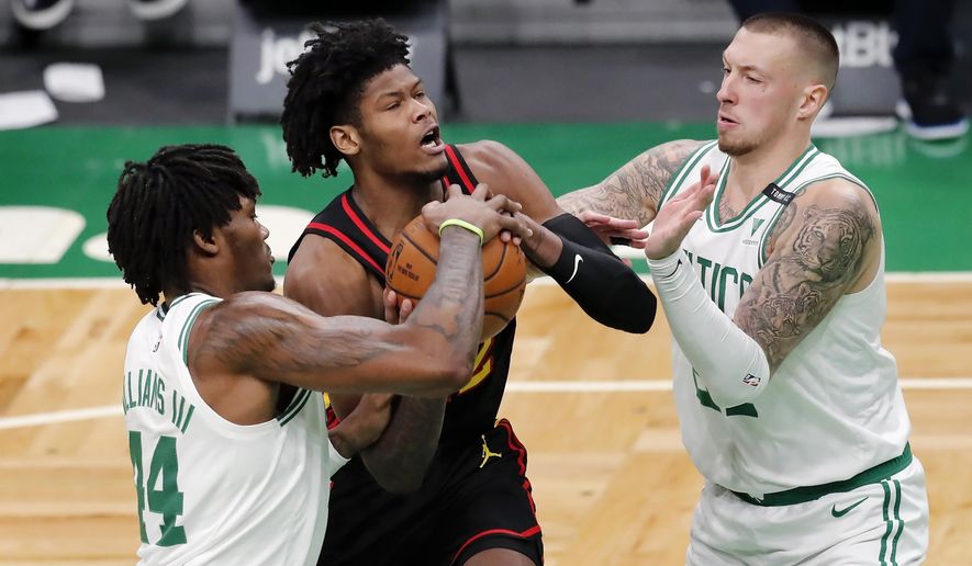 Boston Celtics' Robert Williams III (44) and Daniel Theis, right, block a drive for the basket by Atlanta Hawks' Cam Reddish during the first half of an NBA basketball game Friday, Feb. 19, 2021, in Boston. (AP Photo/Michael Dwyer)