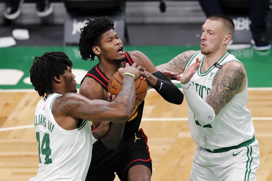 Boston Celtics' Robert Williams III (44) and Daniel Theis, right, block a drive for the basket by Atlanta Hawks' Cam Reddish during the first half of an NBA basketball game Friday, Feb. 19, 2021, in Boston. (AP Photo/Michael Dwyer)