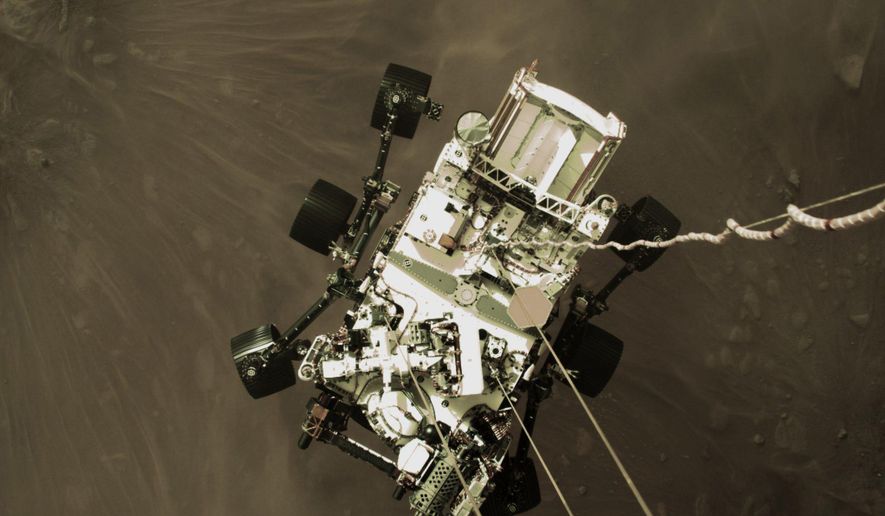 This Thursday, Feb. 18, 2021 photo provided by NASA shows the Perseverance rover lowered towards the surface of Mars during its powered descent. (NASA via AP)