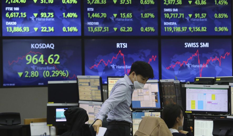 A currency trader talks with his colleague at the foreign exchange dealing room of the KEB Hana Bank headquarters in Seoul, South Korea, Friday, Feb. 19, 2021. Asian stock markets followed Wall Street lower on Friday after disappointing U.S. jobs and economic data. (AP Photo/Ahn Young-joon)