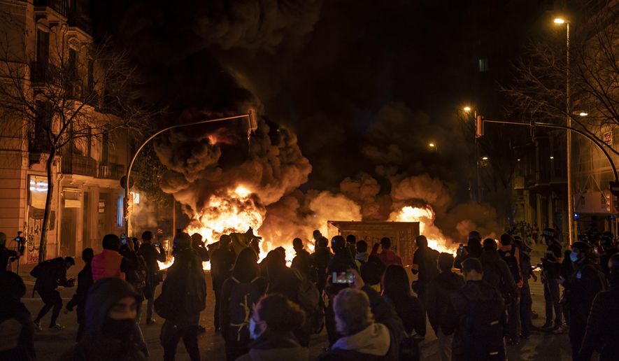 Demonstrators gather near a burning barricade during clashes with police following a protest condemning the arrest of rap singer Pablo Hasél in Barcelona, Spain, Thursday, Feb. 18, 2021. Protests over the imprisonment of a rapper convicted for insulting the Spanish monarchy and praising terrorist violence have morphed for the third night in a row into rioting. Pablo Hasél began this week to serve a 9-month sentence in a northeastern prison. (AP Photo/Felipe Dana)