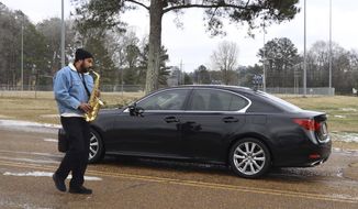 Thomas Johnson, 39, plays his saxophone for a line of cars waiting to pick up bottled water near the medical district in Jackson, Mississippi on Friday, Feb. 19, 2021. Most cars had been at a standstill for hours. Johnson, a musician, put his car in park after waiting for two hours and walked up and down the line of traffic. Almost all of Jackson&#39;s 161,000 residents were without water Friday. (AP Photo/Leah Willingham)
