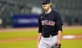 FILE - In this Sept. 17, 2020, file photo, Cleveland Indians pitcher Shane Bieber smiles as he walks to the dugout in the fourth inning of a baseball game against the Detroit Tigers in Detroit. Bieber has reported to training camp with the Cleveland Indians after recovering from COVID-19. The right-hander took part in drills on Saturday, Feb. 20, 2021, a day before the Indians hold their first full-squad workout in Goodyear, Ariz.  (AP Photo/Paul Sancya, File)
