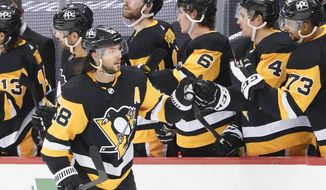 Pittsburgh Penguins&#39; Jake Guentzel (59) is greeted by Cody Ceci (4) and other teammates on the bench after scoring against the New York Islanders during the second period of an NHL hockey game, Saturday, Feb. 20, 2021, in Pittsburgh. (AP Photo/Keith Srakocic)
