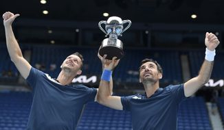 Croatia&#39;s Ivan Dodig, right, and Slovakia&#39;s Filip Polasek hold their trophy aloft after defeating Rajeev Ram of the US and Britain&#39;s Joe Salisbury in the men&#39;s doubles final at the Australian Open tennis championship in Melbourne, Australia, Sunday, Feb. 21, 2021.(AP Photo/Andy Brownbill)