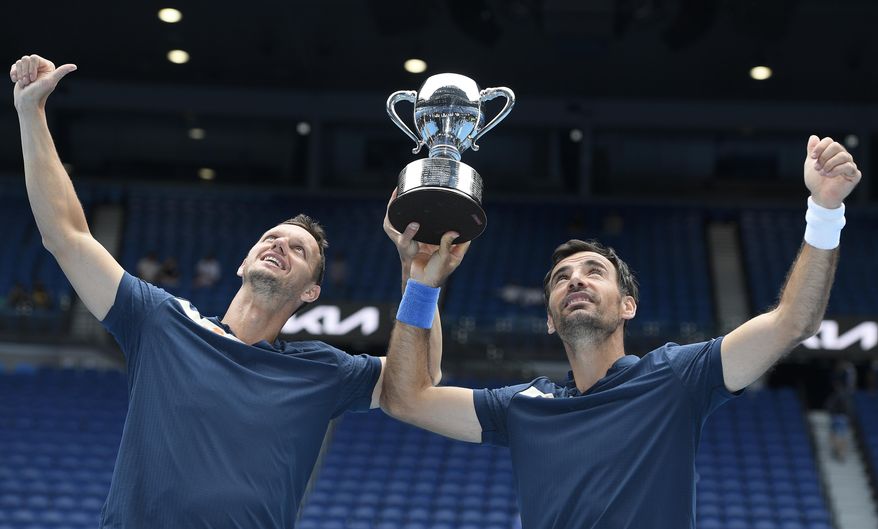 Croatia&#39;s Ivan Dodig, right, and Slovakia&#39;s Filip Polasek hold their trophy aloft after defeating Rajeev Ram of the US and Britain&#39;s Joe Salisbury in the men&#39;s doubles final at the Australian Open tennis championship in Melbourne, Australia, Sunday, Feb. 21, 2021.(AP Photo/Andy Brownbill)