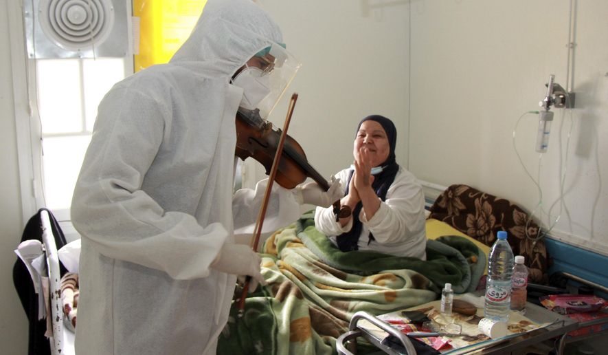 Dr. Mohamed Salah Siala plays the violin for patients on the COVID wards of the Hedi Chaker hospital in Sfax, eastern Tunisia, Saturday Feb. 20, 2021. When the 25-year-old decided to get out his violin one day at Hedi Chaker Hospital in city of Sfax and play, it won praise for boosting the morale of virus sufferers who remained isolated and needed a smile. (AP Photo)