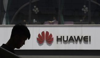 FILE - In this Thursday, May 16, 2019 file photo, a man is silhouetted near the Huawei logo in Beijing. Struggling under U.S. sanctions, Chinese tech giant Huawei has unveiled a new flagship foldable smartphone but says it will only be sold in China.  (AP Photo/Ng Han Guan, File)