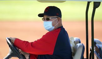 Cleveland Indians manager Terry Francona wears a face covering as he drives around on a golf cart during a spring training baseball practice Monday, Feb. 22, 2021, in Goodyear, Ariz. (AP Photo/Ross D. Franklin)