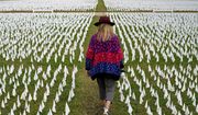 In this Oct. 27, 2020, file photo, Artist Suzanne Brennan Firstenberg walks among thousands of white flags planted in remembrance of Americans who have died of COVID-19 near Robert F. Kennedy Memorial Stadium in Washington. Firstenberg&#39;s temporary art installation, called &amp;quot;In America, How Could This Happen,&amp;quot; will include an estimated 240,000 flags when completed. (AP Photo/Patrick Semansky, File)