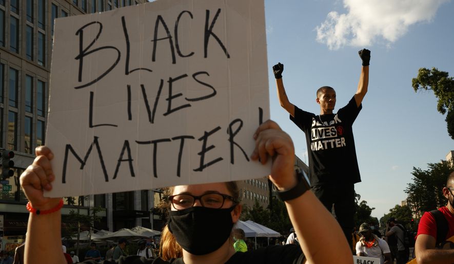 In this June 24, 2020, file photo, Antonio Mingo, of Washington, right, holds his fists in the air as demonstrators protest in front of a police line on a section of 16th Street that&#39;s been renamed Black Lives Matter Plaza in Washington, following the death of George Floyd, a black man who was in police custody in Minneapolis. A financial snapshot shared exclusively with The Associated Press shows the Black Lives Matter Global Network Foundation took in just over $90 million last year. (AP Photo/Jacquelyn Martin, File)