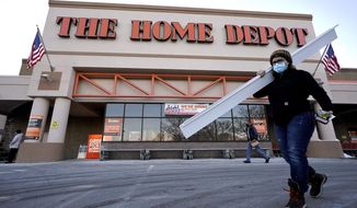Passers-by walk near an entrance to a Home Depot home improvement store Sunday, Feb. 21, 2021, in Boston. The Home Depot’s fiscal fourth-quarter sales surged 25% as the home improvement chain continues to meet the demands of consumers stuck at home and a resilient housing market. (AP Photo/Steven Senne)