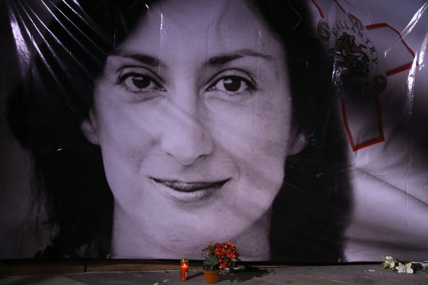 FILE - In this Tuesday, Oct. 16, 2018 file photo, flowers and a candle lie in front of a portrait of slain investigative journalist Daphne Caruana Galizia during a vigil outside the law courts in Valletta, Malta. One of three men accused of killing Maltese investigative journalist Daphne Caruana Galizia in a 2017 car bombing changed his plea to guilty during a hearing Tuesday and was immediately sentenced to 15 years in prison. The man, Vince Muscat, together with Alfred and George Degiorgio, had been accused of detonating the bomb that killed Caruana Galizia as she was driving her car Oct. 16, 2017. (AP Photo/Jonathan Borg, File)