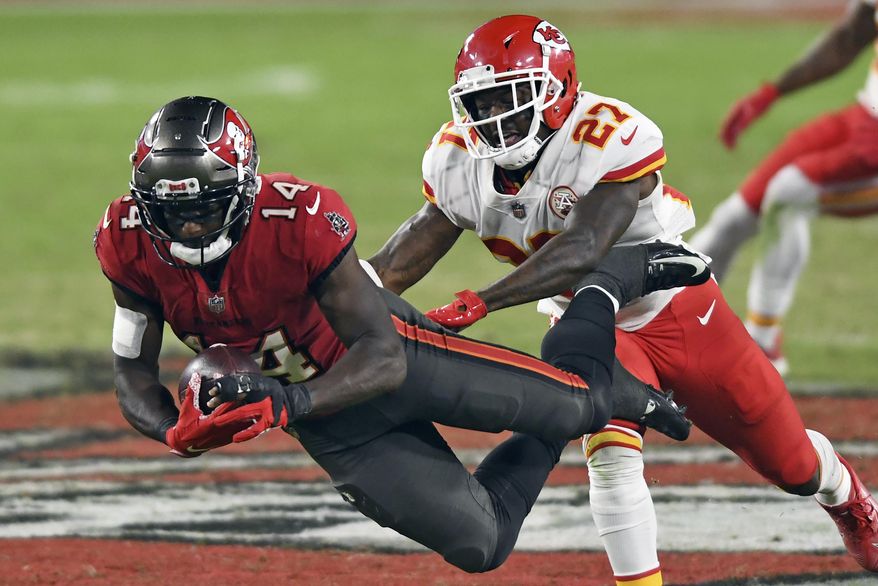 FILE - In this Sunday, Nov. 29, 2020 file photo, Tampa Bay Buccaneers wide receiver Chris Godwin (14) makes a diving catch in front of Kansas City Chiefs cornerback Rashad Fenton (27) during the second half of an NFL football game in Tampa, Fla. Applying franchise and even transition tags to players can have major ramifications on a team's present and future. That was never more of a consideration than this year, with the salary cap decreasing by, for now, $18 million. That's the first time the cap has gone down, which is due to lost revenues caused by the COVID-19 pandemic.(AP Photo/Jason Behnken, File)