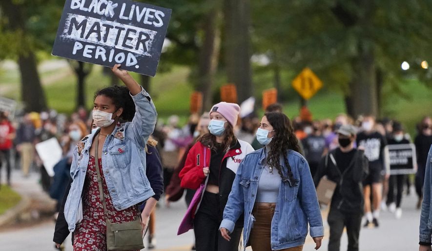 A woman holds up a sign during q protest, Tuesday, Sept. 29, 2020, in Cleveland. Racism would be declared a public health crisis in Ohio and the day celebrating the official end of slavery would become a paid state holiday under racial justice measures reintroduced Tuesday, Feb. 23, 2021, after unsuccessful efforts to pass them during the last legislative session. (AP Photo/Tony Dejak, File)