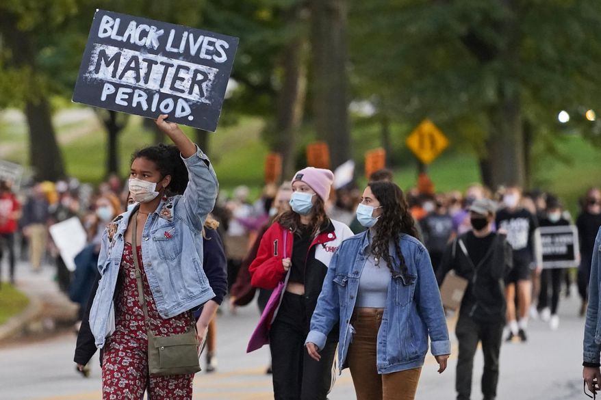 A woman holds up a sign during q protest, Tuesday, Sept. 29, 2020, in Cleveland. Racism would be declared a public health crisis in Ohio and the day celebrating the official end of slavery would become a paid state holiday under racial justice measures reintroduced Tuesday, Feb. 23, 2021, after unsuccessful efforts to pass them during the last legislative session. (AP Photo/Tony Dejak, File)