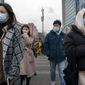 People wearing face masks to protect against the spread of the coronavirus walk across a street in Beijing, Tuesday, Feb. 23, 2021. China has been regularly reporting no locally transmitted cases of COVID-19 as it works to maintain control of the pandemic within its borders. (AP Photo/Mark Schiefelbein)