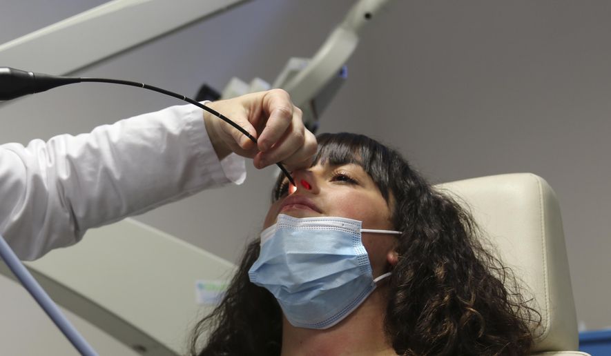 In this file photo, Gabriella Forgione, a 25-year-old patient, holds still as a doctor slides a miniature camera up her nose during tests in a hospital in Nice, France, on Monday, Feb. 8, 2021, to help determine why she has been unable to smell or taste since she contracted COVID-19 in November 2020. According to a study published in Nov. 2021, more than 1 million people in the U.S. who contracted COVID-19 might have lost their sense of smell for six months or longer, a new study revealed. (AP Photo/John Leicester)  **FILE**