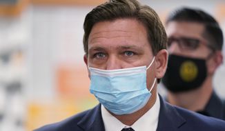 Wearing a mask to prevent the spread of COVID-19, Florida Gov. Ron DeSantis looks on during a news conference, Tuesday, Feb. 23, 2021, at a Navarro Discount Pharmacy in Hialeah, Fla. DeSantis announced that seniors will soon be able to receive COVID-19 vaccinations at Navarro Discount Pharmacies and CVS y mas pharmacies in Miami-Dade County. (AP Photo/Wilfredo Lee)