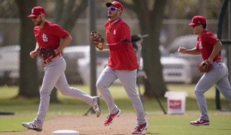 St. Louis Cardinals infielder Nolan Arenado, center, jogs out to the field with teammates Paul DeJong, left, and Tommy Edman during spring training baseball practice Monday, Feb. 22, 2021, in Jupiter, Fla. (AP Photo/Jeff Roberson)