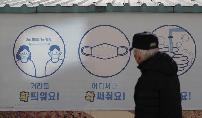 A man wearing a face mask, looks at a banner displaying precautions against the coronavirus in Goyang, South Korea, Wednesday, Feb. 24, 2021. The letters read &amp;quot;Mandatory mask wearing.&amp;quot; (AP Photo/Lee Jin-man)