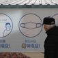 A man wearing a face mask, looks at a banner displaying precautions against the coronavirus in Goyang, South Korea, Wednesday, Feb. 24, 2021. The letters read &amp;quot;Mandatory mask wearing.&amp;quot; (AP Photo/Lee Jin-man)