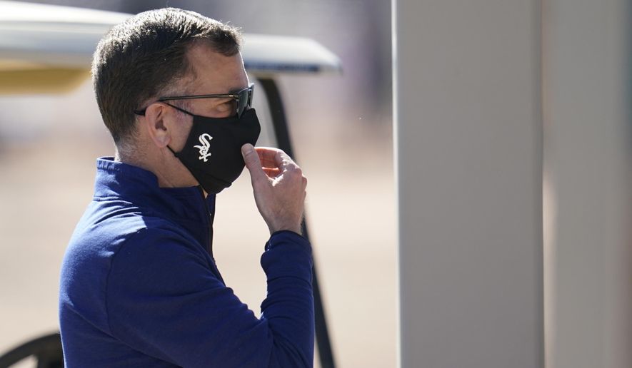 Chicago White Sox general manager Rick Hahn adjusts his face covering as he watches players during baseball spring training Wednesday, Feb. 24, 2021, in Phoenix. (AP Photo/Ross D. Franklin)