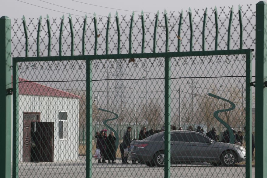 FILE - In this Monday, Dec. 3, 2018, file photo, people line up at the Artux City Vocational Skills Education Training Service Center at the Kunshan Industrial Park in Artux in western China's Xinjiang region. A small core of international lawyers and activists are prodding leading Olympic sponsors to acknowledge China's widely reported human-rights abuses against Muslim Uyghurs, Tibetans and other minorities.(AP Photo/Ng Han Guan, File)