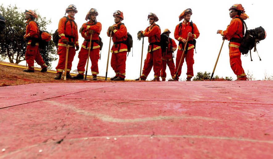 FILE - In this Aug. 17, 2020, file photo, inmate firefighters - notable by their bright orange fire gear compared to the yellow worn by professional firefighters - prepare to take on the River Fire in Salinas, Calif. California could change its constitutional ban on slavery to remove the words "unless for the punishment of crime," further reducing the state's already faltering dependence on thousands of inmate firefighters, under a proposed amendment backed Thursday, Feb. 25, 2021, by local officials and actor-activist Danny Glover. (AP Photo/Noah Berger, File)