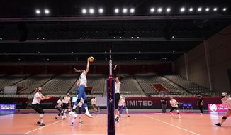 Right side hitter Karsta Lowe, left, watches as middle blocker Lauren Gibbemeyer, top left, makes a hit during volleyball practice in Dallas, Wednesday, Feb. 24, 2021. U.S.  (AP Photo/Tony Gutierrez)