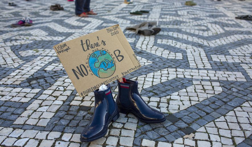 Pairs of shoes with messages about environment protection are placed by activists evenly spaced over a square in Lisbon during a global climate protest, Friday, Sept. 25, 2020. (AP Photo/Armando Franca)