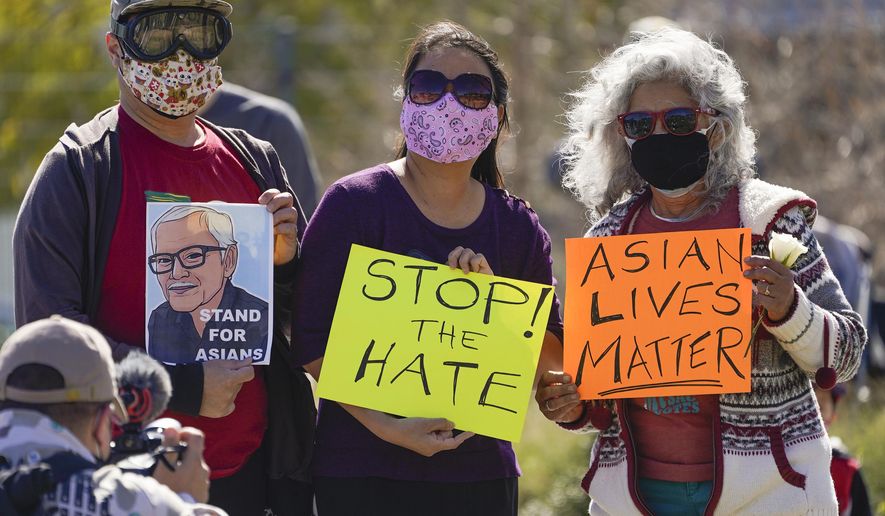 A man holds a portrait of late Vichar Ratanapakdee, left, a 84-year-old immigrant from Thailand, who was violently shoved to the ground in a deadly attack in San Francisco, during a community rally to raise awareness of anti-Asian violence and racist attitudes, in response to the string of violent racist attacks against Asians during the pandemic, held at Los Angeles Historic Park near the Chinatown district in Los Angeles, Saturday, Feb. 20, 2021. (AP Photo/Damian Dovarganes)