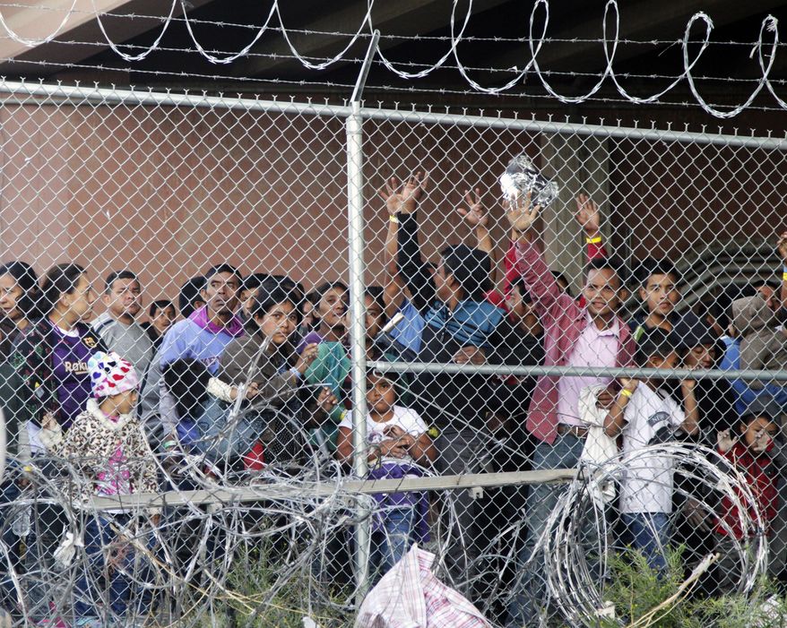 In this March 27, 2019, file photo, Central American migrants wait for food in a pen erected by U.S. Customs and Border Protection to process a surge of migrant families and unaccompanied minors in El Paso, Texas. (AP Photo/Cedar Attanasio, File)
