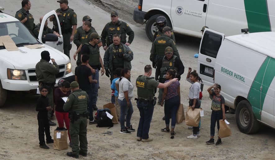 A girl waves to a young man watching from Mexican territory who said he was her cousin, as a group of Honduran asylum seekers is taken into custody by U.S. Border Patrol agents after the group crossed the U.S. border wall into San Diego, California, seen from Tijuana, Mexico. (AP Photo/Rebecca Blackwell, File)
