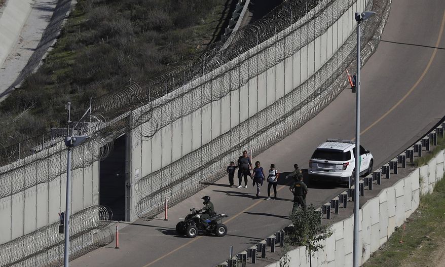 FILE - In this Dec. 16, 2018, file photo, Honduran asylum seekers are taken into custody by U.S. Border Patrol agents after the group crossed the U.S. border wall into San Diego, in California, seen from Tijuana, Mexico. The state of California is freeing up to $28 million to help asylum-seekers released in the U.S. with notices to appear in court with hotels, medical screenings, and transportation. California&#39;s generosity is a stark contrast to Arizona and Texas, where border state officials have challenged and sharply criticized President Joe Biden&#39;s immigration policies. (AP Photo/Moises Castillo, File)