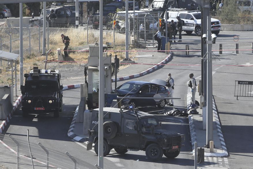 FILE - In this June 23, 2020, file photo, Israeli policemen stand around the body of a Palestinian at a checkpoint near Jerusalem. Israeli police previously said that Ahmed Erekat, a 27-year-old print shop owner, rammed his car into a checkpoint in a terrorist attack and later died of wounds following gunfire from police. Earlier this week, Forensic Architecture, a London-based group that investigates state violence, and Palestinian human rights group Al Haq said its analysis raises major questions in the Israeli army’s claim about Ahmad’s killing and calls for further investigation. (AP Photo/Mahmoud Illean, File)