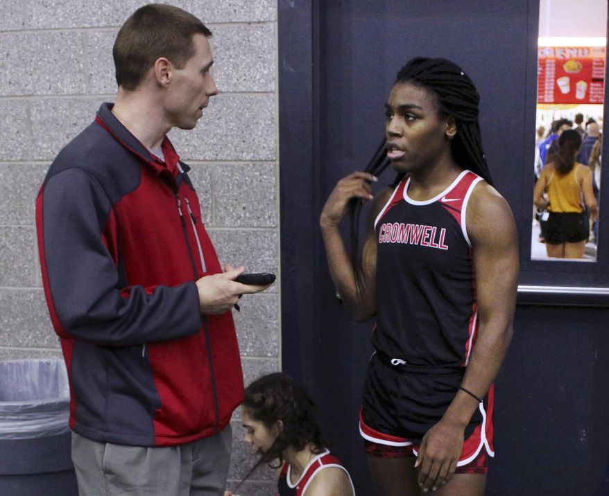 FILE — In this Feb. 7, 2019 file photo, Cromwell High School track coach Brian Calhoun, left, speaks to transgender athlete Andraya Yearwood during a break at a meet at Hillhouse High School in New Haven, Conn. Lawyers for several Connecticut school districts and the organization that oversees high school sports in the state went before a federal judge Friday, Feb. 26, 2021, seeking the dismissal of a lawsuit that would prevent transgender girls from competing in girl's sports. (AP Photo/Pat Eaton-Robb, File)