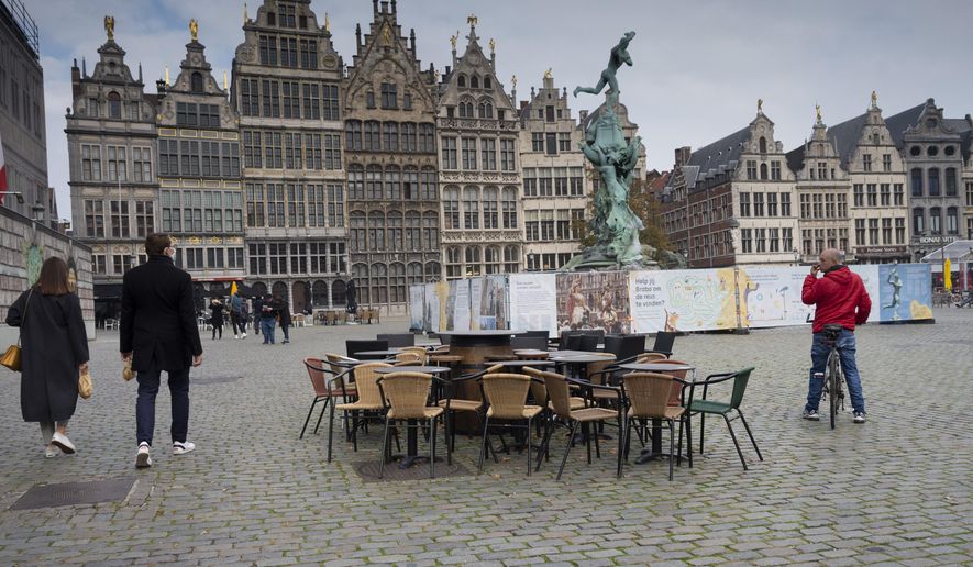 FILE - In this Monday, Oct. 20, 2020 file photo, people walk by chairs and tables of an empty terrace in the historical center of Antwerp, Belgium. Belgian health authorities warned Friday, Feb. 26, 2021 that the number of coronavirus infections is rising as the government appeared set to prolong restrictions for several more weeks. (AP Photo/Virginia Mayo, File)