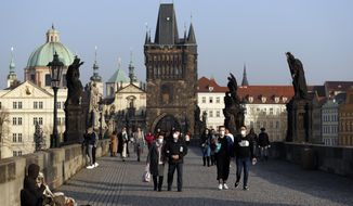 People wearing face masks walk across the medieval Charles Bridge in Prague, Czech Republic, Thursday, Feb. 25, 2021. The Czech government is barring the citizens and residents from travelling to the countries hit by highly contagious coronavirus variants and is tightening the rules for face coverings. Starting on Thursday, the Czechs are required to wear better masks in places where large numbers gather, including stores, hospitals and public transportation. (AP Photo/Petr David Josek)