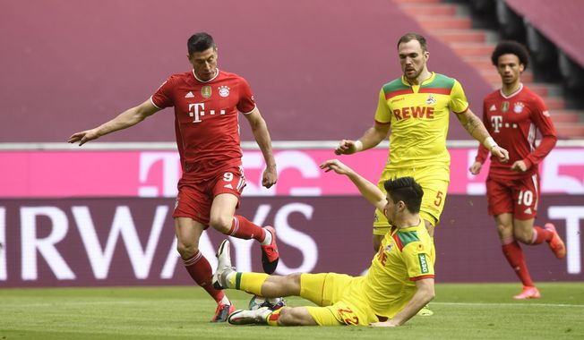 Bayern&#x27;s Robert Lewandowski (l) and Koeln&#x27;s Jorge Meré challenge for the ball during a German Bundesliga soccer match between Bayern Munich and 1.FC Cologne in Munich, Germany, Saturday, Feb. 27, 2021. (AP Photo/Andreas Schaad)