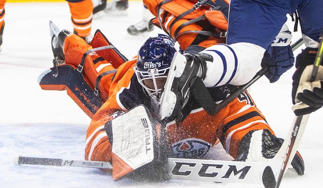 Edmonton Oilers goalie Mike Smith (41) makes the save as he is hit with a skate from a Toronto Maple Leafs player during the first period of an NHL game in Edmonton, Alberta, on Saturday, Feb. 27, 2021. (Jason Franson/The Canadian Press via AP)